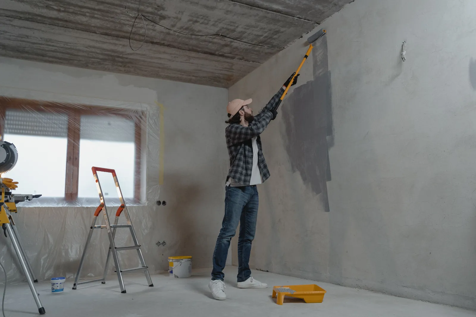 Painter applying a new wall color with a roller in a protected interior room.