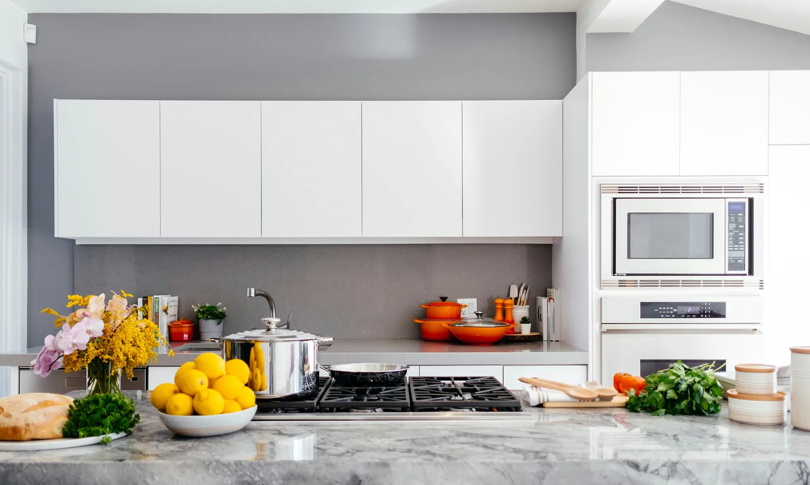 Modern kitchen with smooth white cabinet fronts and a contrasting gray painted wall.