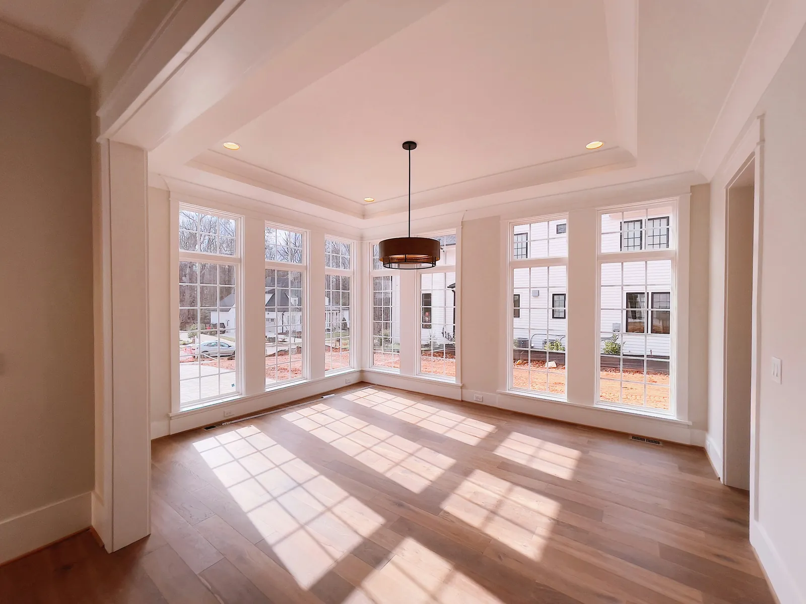Sunlit interior with light painted walls, white trim, windows, and detailed ceiling molding.