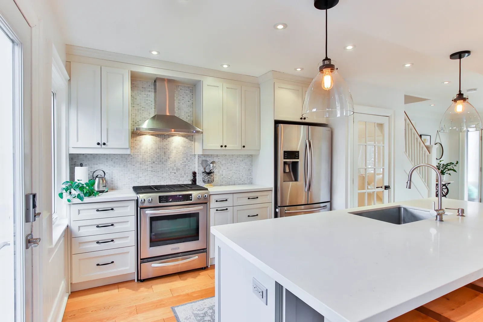 Finished kitchen with white painted cabinets, dark hardware, and light countertops.